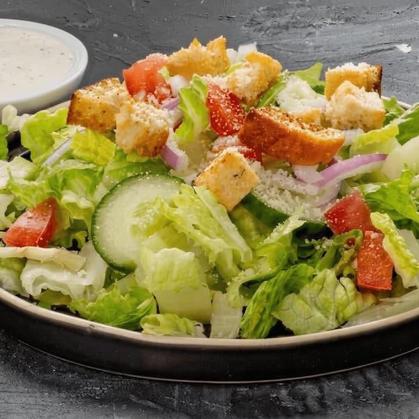 Fresh garden salad with lettuce, tomatoes, cucumbers, red onions, croutons, and parmesan cheese.
